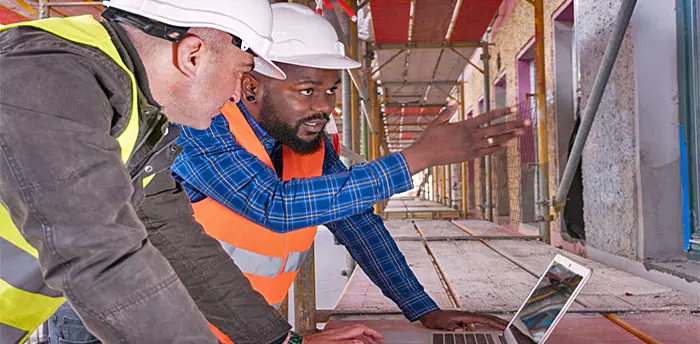 Two inspectors discussing code safety, in construction area with framing