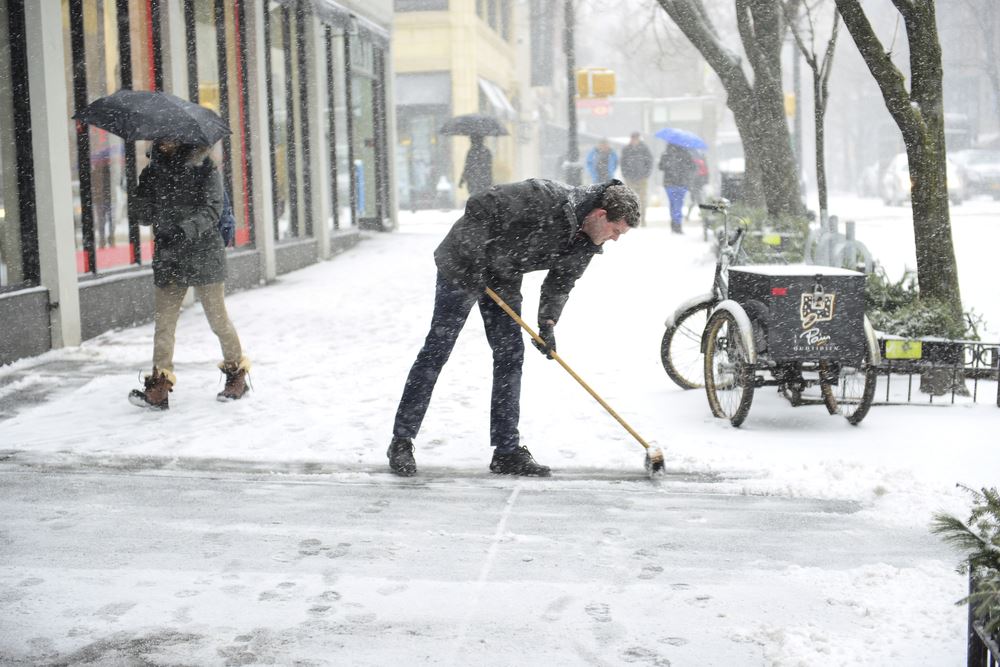 Man Brushing the Snow Off the Sidewalk