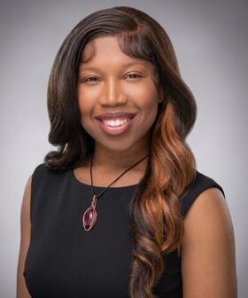 Headshot of Jordan Anderson smiling against gray gradient background