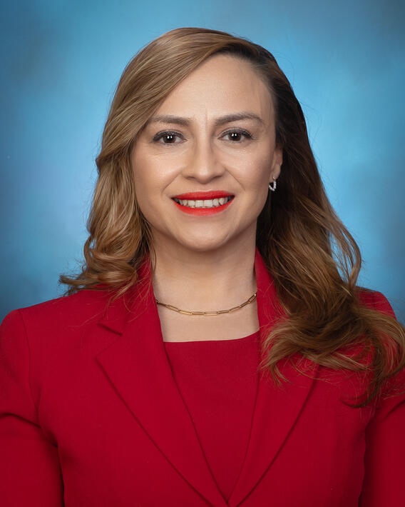 Headshot of a woman smiling wearing a red outfit with a blue background