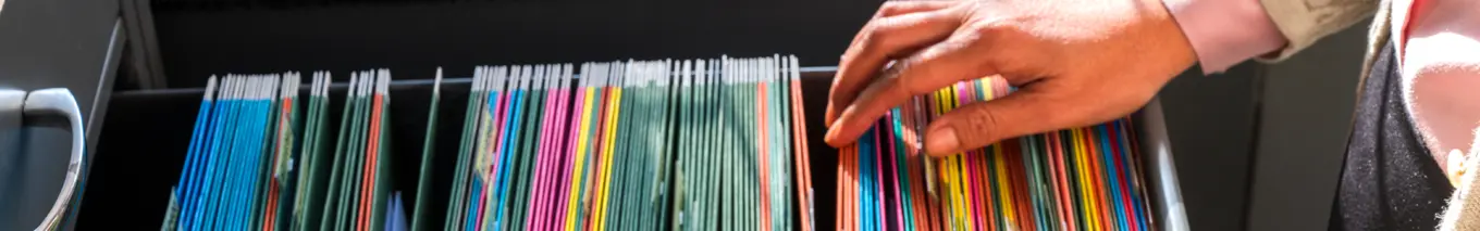 A person searching through files in a file cabinet. 