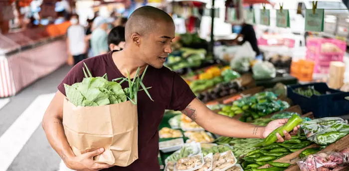 Food Service Facility Permit includes farmers market permits, photo of young man selecting produce at a farmers market