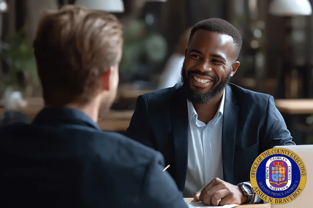 Two men talking acrss from one another, one smiling and the other with his head to the camera