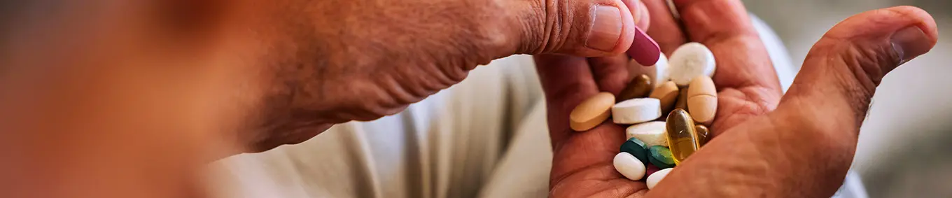 An elderly person with a chronic disease taking his daily medication.