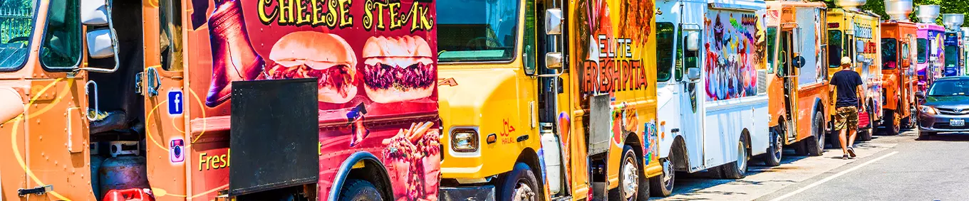 A line of food trucks parked serving customers.