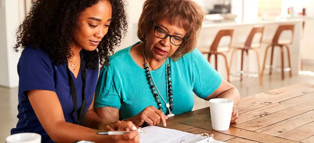 Nurse helping older lady with paperwork. 