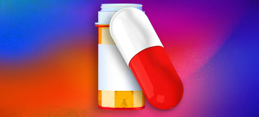 A pill bottle and a pill in front of a colorful background.