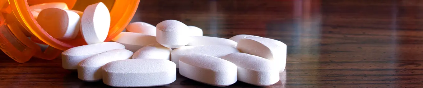 A photo of pills spilling out of a prescription pill bottle, depicting opioid addiction.