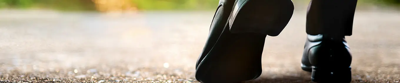A man stepping forward in dress shoes and slacks into a brighter future.