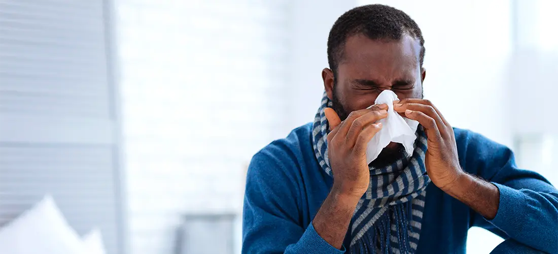 Man blowing nose with a tissue. 