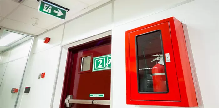 Safety equipment mounted and ready for inspection, hallway with fire alarm, extinguisher and exit sign