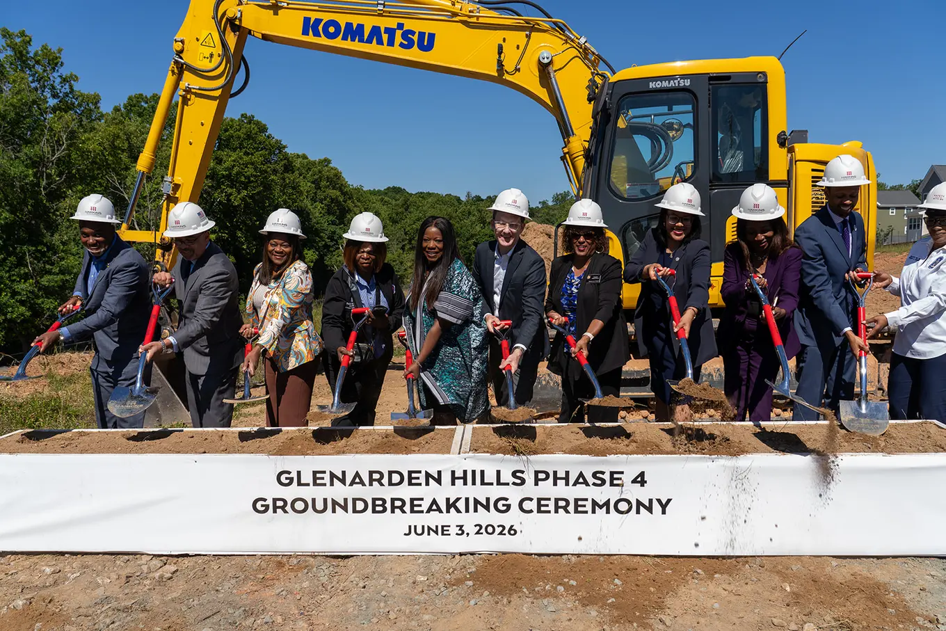 Glenarden Hills Phase 4 team of 11 individuals posing with shovels with an excavator behind them
