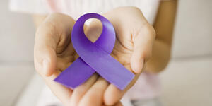 Two hands holding a purple domestic violence awareness ribbon