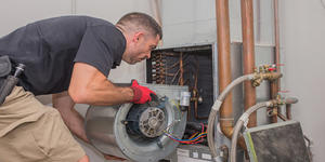 Mechanical trade worker, HVAC, man installing new motor in furnace