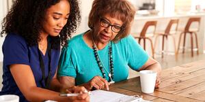 Nurse helping older lady with paperwork. 