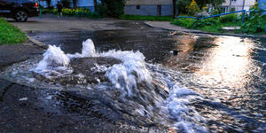 A sewer manhole overflowing with water in a neighborhood. 