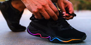 A man lacing up his running sneakers with a colorful stripe on the side, getting ready to take a jog.