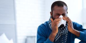 Man blowing nose with a tissue. 