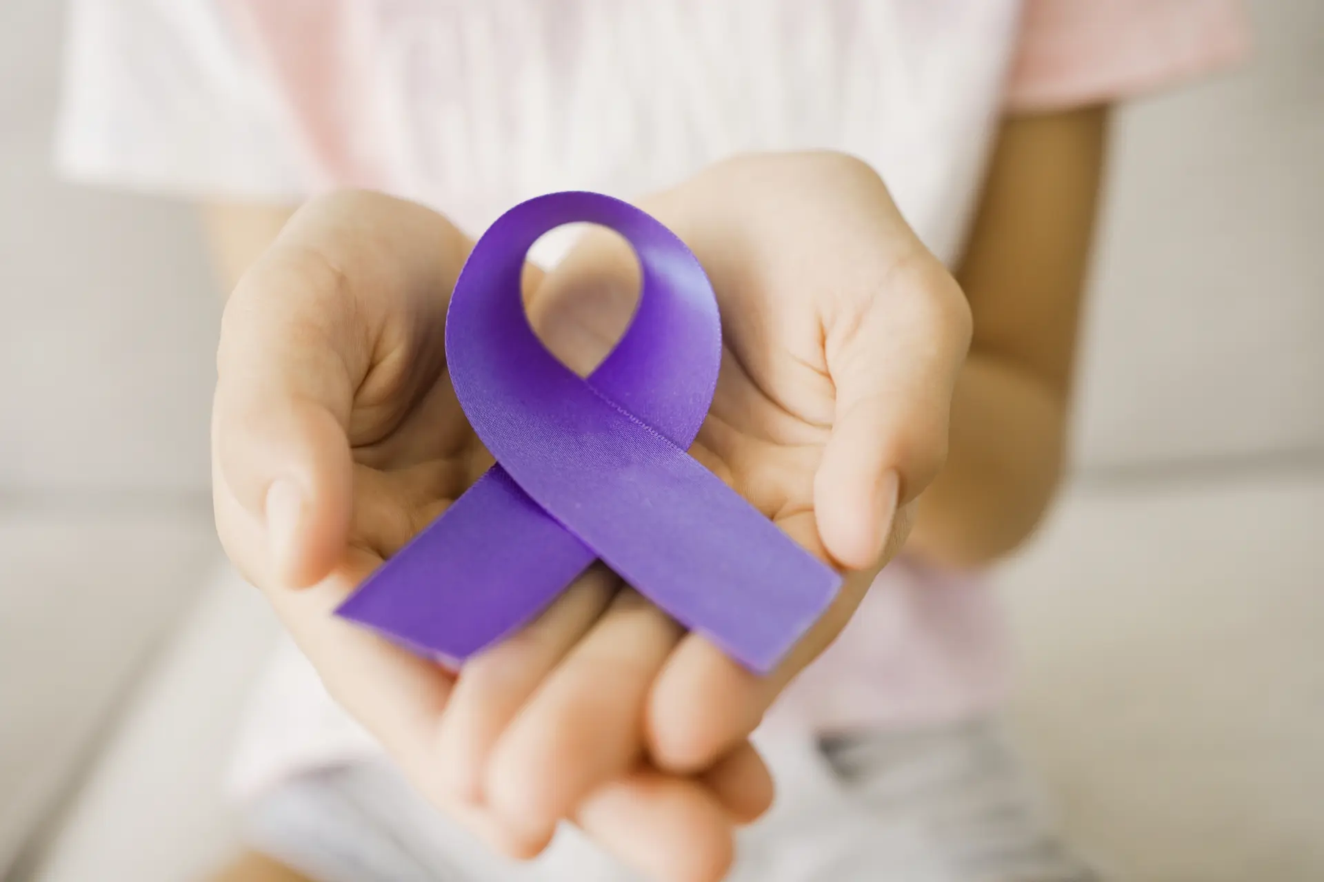 Two hands holding a purple domestic violence awareness ribbon