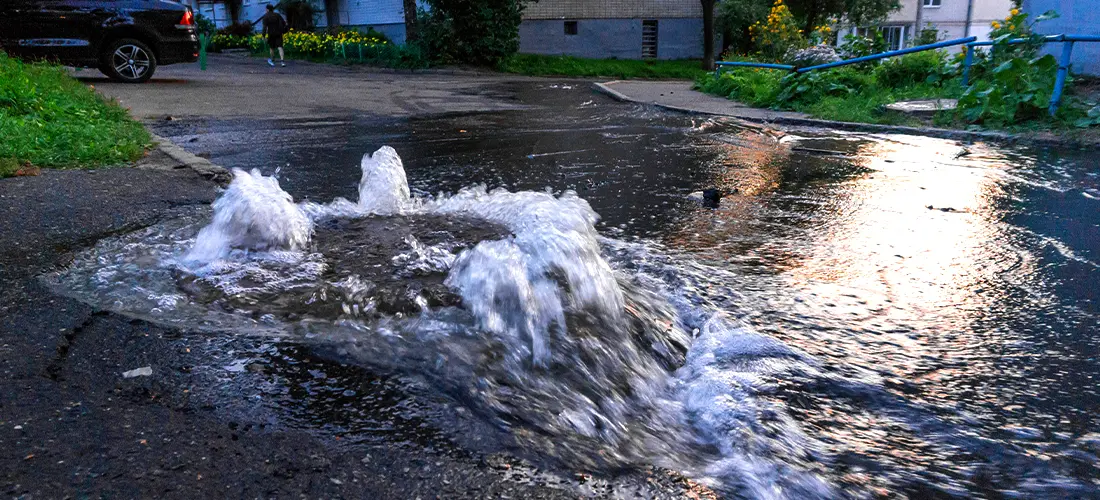 A sewer manhole overflowing with water in a neighborhood. 