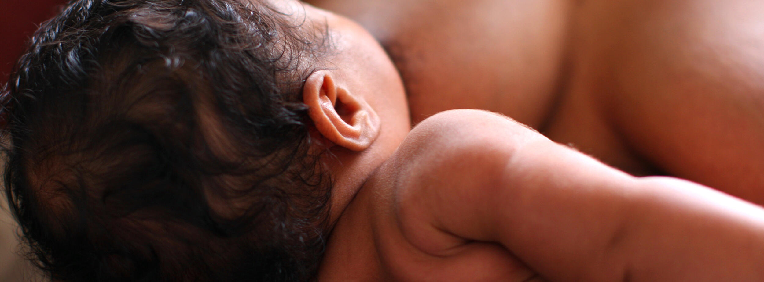 woman in a christmas sweater with her fingers rubbing the bridge of her nose appearing stressed.National Breastfeeding Month